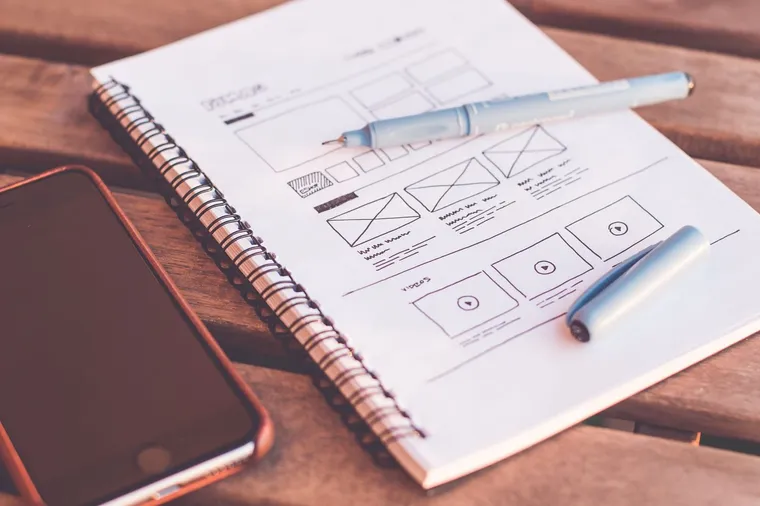 Website wireframe sketch beside a phone